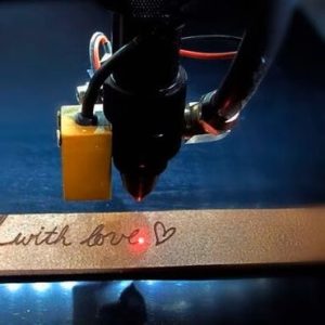 Laserkop graveert de tekst with love in een houten plank